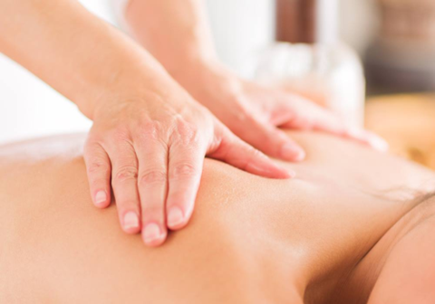 Close up of two hands massaging a person’s upper back